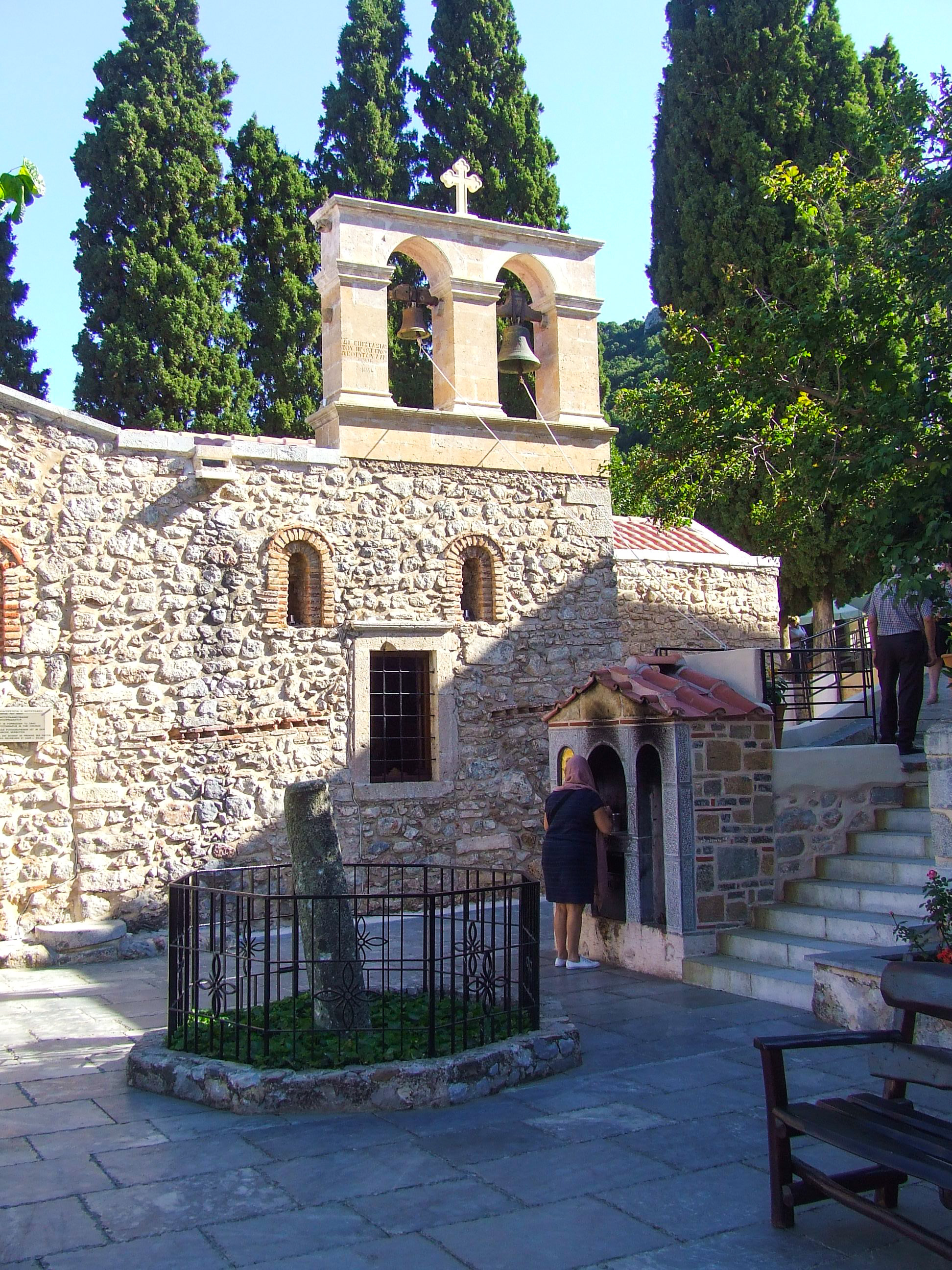 rustic stone church with a bell tower topped with a cross